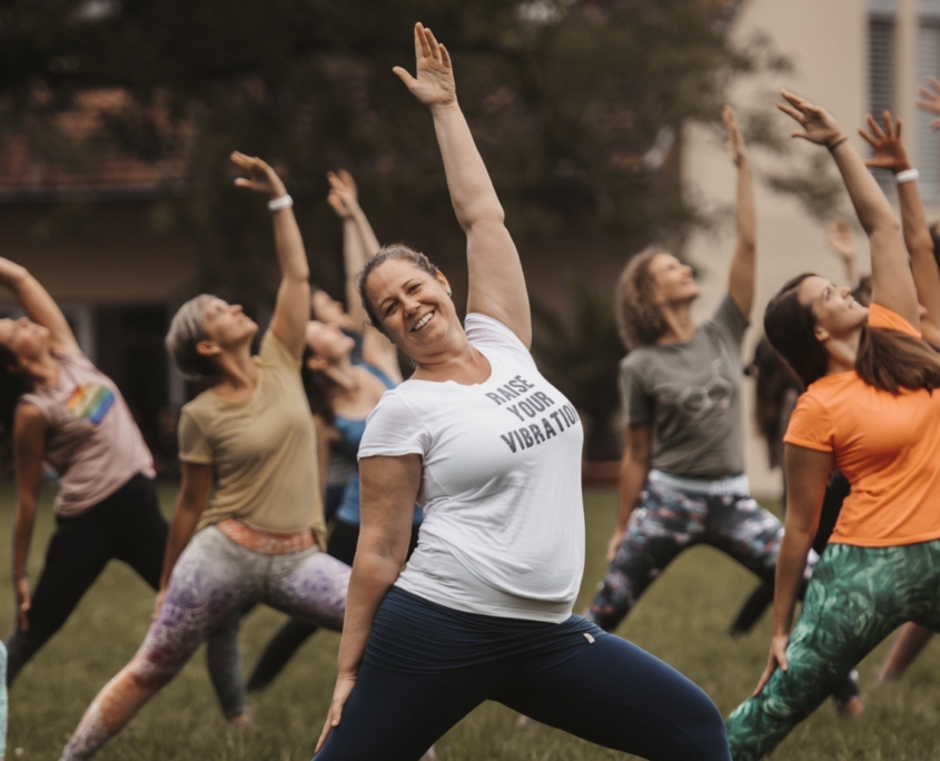 Christine Stiessel steht vor einer Gruppe Yoga-Schülerinnen und alle stehen in der gleiche Asanas